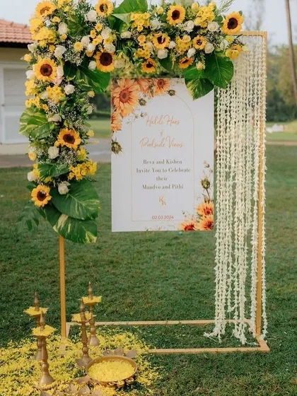 This welcome sign for a Haldi is framed by a beautiful arch of sunflowers and other foliage, with traditional lamps at the base. It sets a warm and inviting tone right from the entrance.