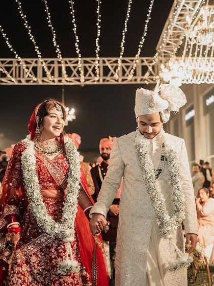A candid moment of the happy couple walking hand-in-hand, with the beautifully lit reception decor creating a magical atmosphere around them.