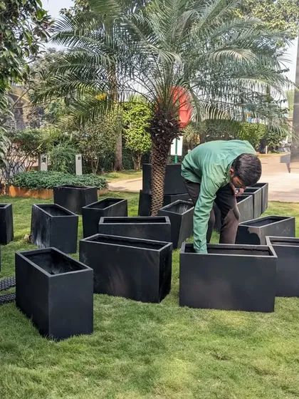 I am organizing the unboxed planters, getting them ready for placement. This systematic approach helps us work efficiently on large project sites.