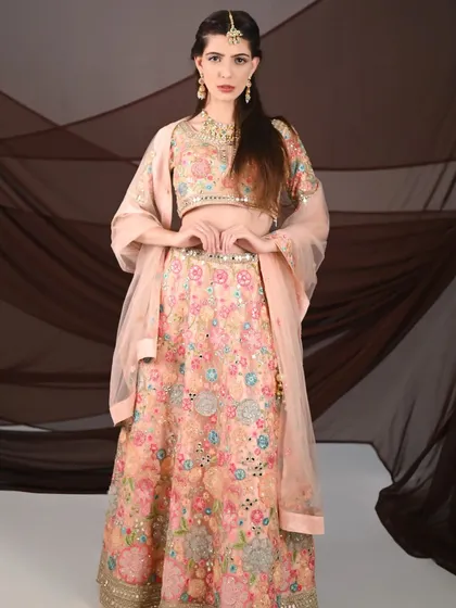 A full-length view of the peach floral lehenga, showing its graceful fall and elegant design. A perfect rental for a summer wedding guest.