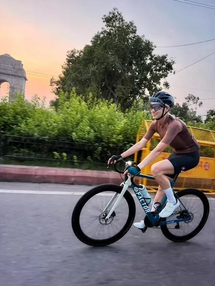 Confidence on two wheels. A member of our cycling club enjoys an early morning ride through the heart of the city, with the iconic India Gate in the background.