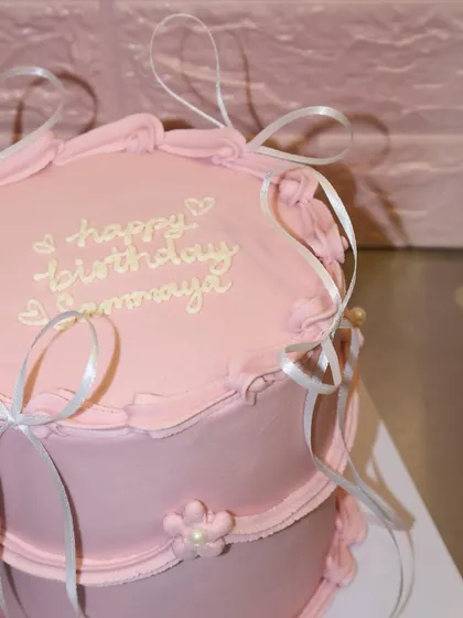 A closer look at the hand-piped "happy birthday" message and delicate ribbon details on this sweet first birthday cake.