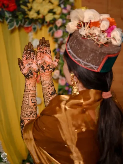 A beautiful shot of a Himachali bride showing her Mehandi, with a focus on her traditional 'Pahari' cap.