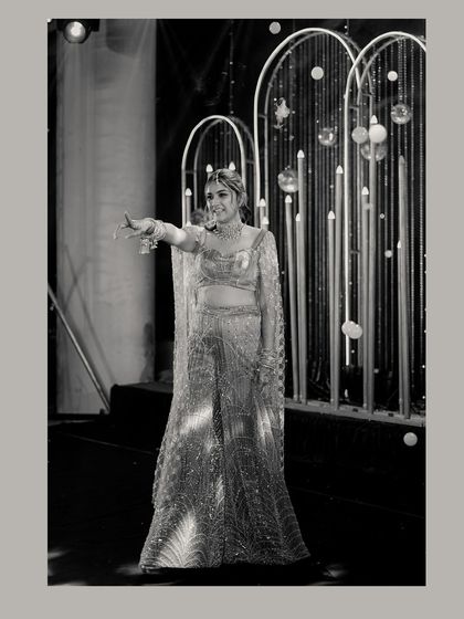 A black and white portrait of the bride on the Sangeet stage, her pose full of grace and elegance.