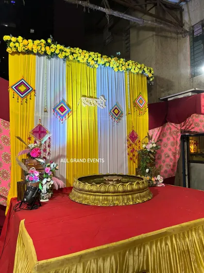 The Haldi ceremony stage, complete with a red carpet and floral arrangements on wooden crates. This setup is perfect for outdoor or large indoor venues.