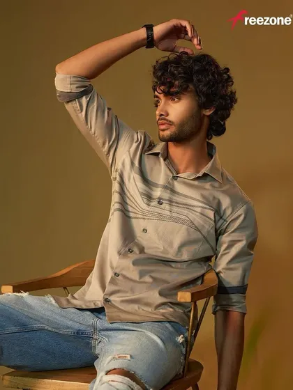 A relaxed, seated portrait for Freezone casual wear. The grooming is natural, enhancing the model's features while maintaining a rugged, masculine look.