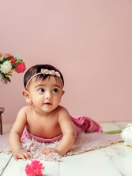 Tummy time is a big milestone too. This pose shows off her strength and curiosity against the soft pink backdrop.