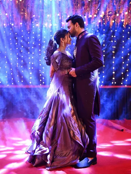 A romantic shot of the couple during their Sangeet night. The dramatic blue lighting and the groom's gentle kiss create a magical, fairytale-like moment.