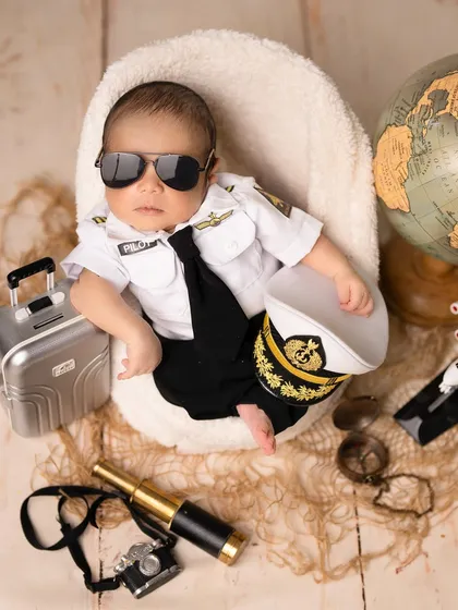 Our little pilot is ready for takeoff. This aviator theme, complete with a captain's hat, a mini suitcase, and a globe, is perfect for families who love to travel and dream of adventure.