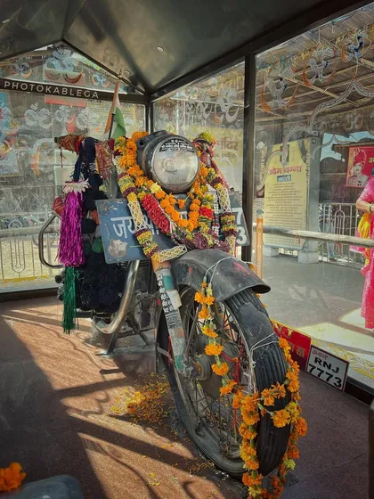 A close-up of the worshipped Royal Enfield, adorned with garlands and offerings.