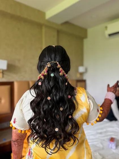 The back view of the Haldi hairstyle, showing the intricate accessory and the beautiful, bouncy waves.