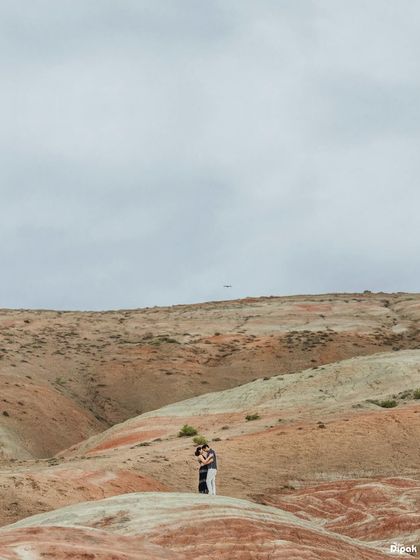 A breathtaking wide-angle shot of a couple embracing amidst the vast, colorful hills of Azerbaijan. This type of epic landscape photography is a key part of my destination shoots.