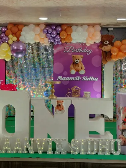 A teddy bear themed first birthday party with large 'ONE' letters as the centerpiece. The purple and orange color scheme offers a unique twist on a classic theme.