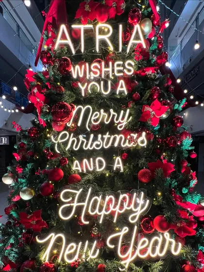 A close-up of the custom neon sign on the Christmas tree. This element added a contemporary and personal touch to the installation, displaying the mall's holiday message in bright, inviting script.