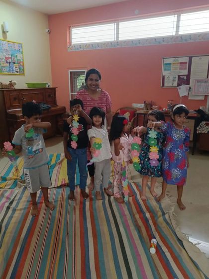 A group of children proudly holds up the beautiful flower garlands they made.