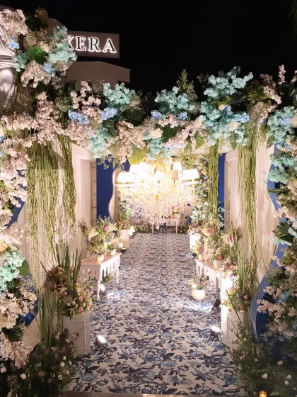 The exterior view of the entrance arch, lavishly decorated with blue and white flowers and greenery, creating a fairytale-like welcome.