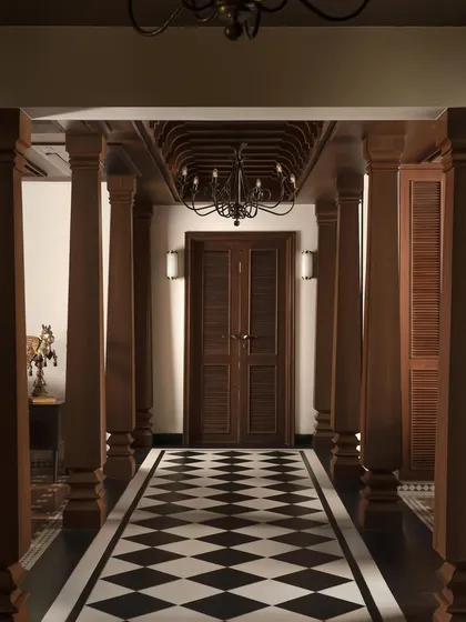 The entry passage of the House of Gond in Pune, where traditional Indian craftsmanship is the protagonist. The corridor, flanked by meticulously carved Chettinad teak pillars, sets a narrative of heritage and artistry that unfolds throughout the home.