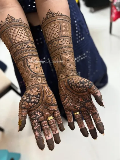 A full bridal set extending up to the elbows. This design features symmetrical patterns on both hands, with a mix of geometric grids on the forearm and floral work on the palms.