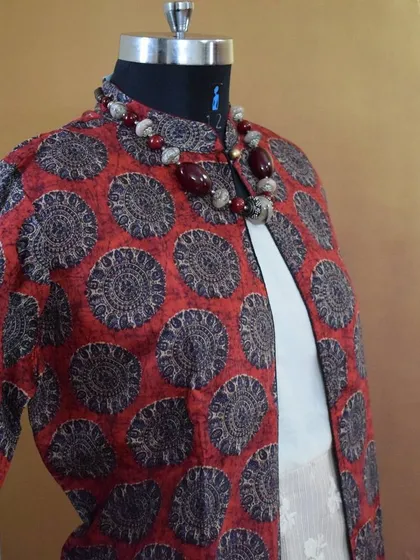 An angled view of the red and black printed jacket, highlighting the mandarin collar and the rich texture of the poly-silk fabric.