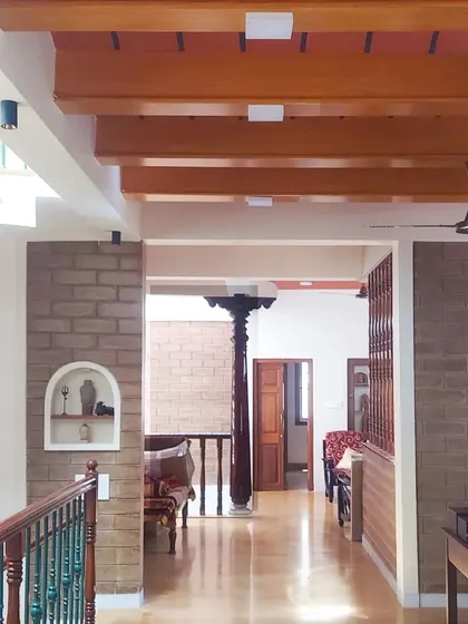 An open hallway view, showing how different spaces flow into one another, with exposed beams, mud block walls, and a traditional pillar in the distance.