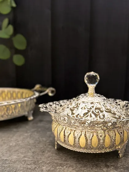 The lidded bowl, with its beautiful cutwork and enamel accents, is a work of art. It is a piece that commands attention on any festive table.