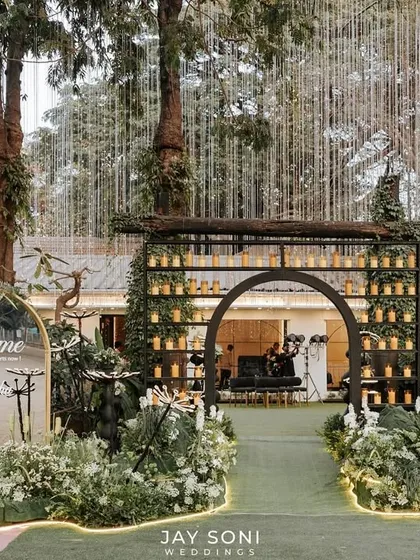 I designed this chic and modern engagement entrance to be an experience in itself. A candle-lined archway, a personalized welcome sign, and whimsical light installations guide guests through a garden of white florals into the event.
