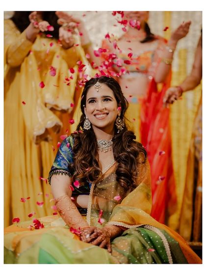 A beautiful portrait of the bride seated, smiling as petals rain down on her.
