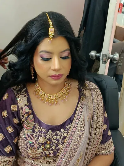 Our stylist puts the finishing touches on a client's party hairstyle. This behind the scenes shot shows the care we take in perfecting every detail, from the makeup to the soft curls in her hair.