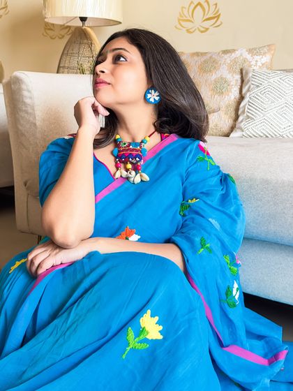 A thoughtful pose in my blue mul saree. I paired it with a quirky, colorful fabric necklace that picks up the embroidery colors perfectly.