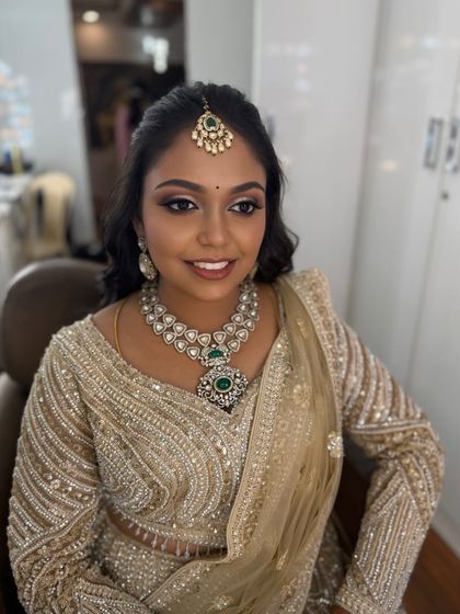 My beautiful bride Prithivi looking glamorous for her reception. Her makeup features a dramatic double-winged eyeliner and a soft, shimmery eyeshadow, paired with a stunning gold lehenga.