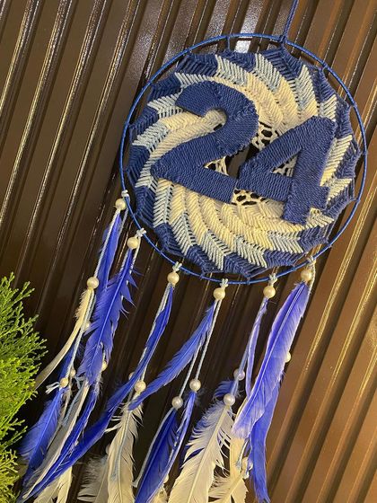 Another view of the lucky number 24 dreamcatcher, this time styled next to a small plant, showing how it can be incorporated into your home decor.
