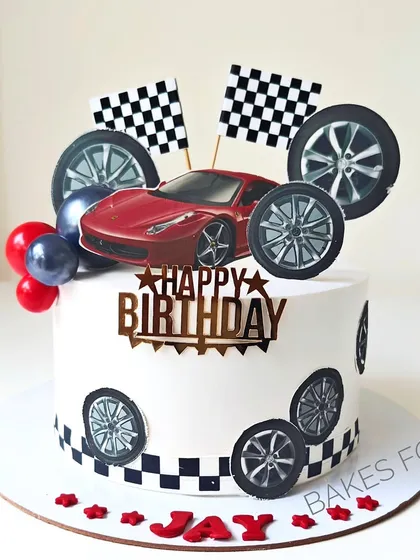 A fun Ferrari-themed cake for a car lover, complete with a red sports car topper, checkered flags, and wheels.