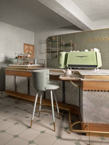 The bar at 11 Grams features a stunning marble-clad front with scalloped wood trim and brass details. The custom-designed bar stool has a soft, modern silhouette that contrasts beautifully with the classic materials.