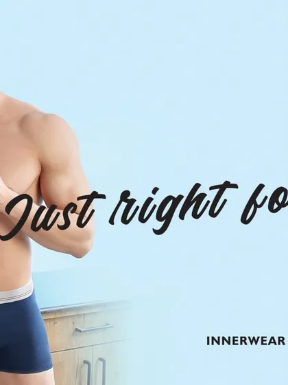 This campaign image for V-Star focuses on men's innerwear. The model is styled to look comfortable and confident, holding a coffee mug to create a simple, relatable morning routine scene.