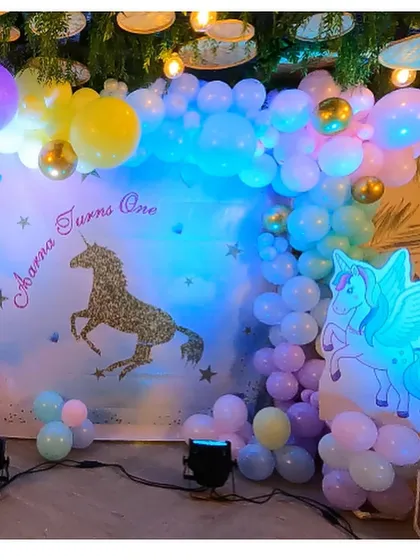 A whimsical Unicorn-themed backdrop with a glitter unicorn silhouette, pastel balloon clouds, and a character cutout.