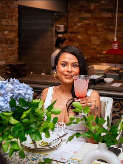 A guest raises her glass, surrounded by flowers and candlelight, a picture of elegance and enjoyment.