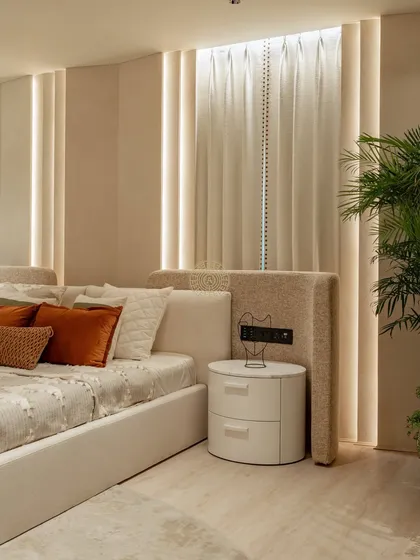 This bedroom in a Kolkata home is designed as a quiet retreat. We used an extended, upholstered headboard and vertical strips of indirect lighting to create a soft, ambient glow and a sense of height.