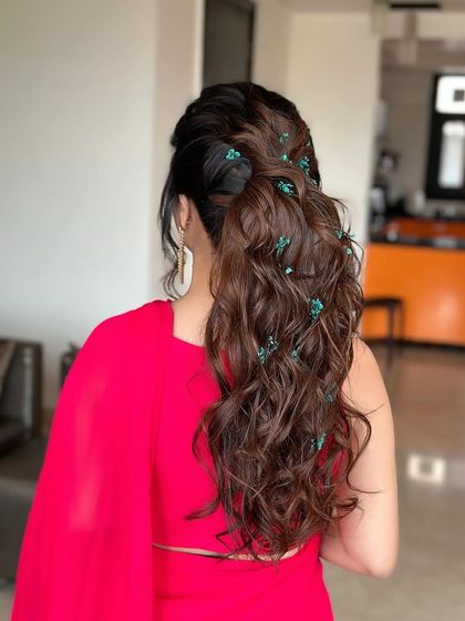 A playful, textured ponytail with small floral accessories scattered throughout. This is a fun and youthful style, perfect for a daytime event or Mehendi.