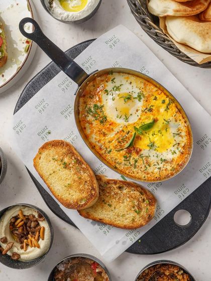 A classic Shakshuka, shot from a top down perspective. The vibrant red of the tomato sauce contrasts beautifully with the bright yellow egg yolks. The crusty bread on the side makes it a complete, inviting meal.