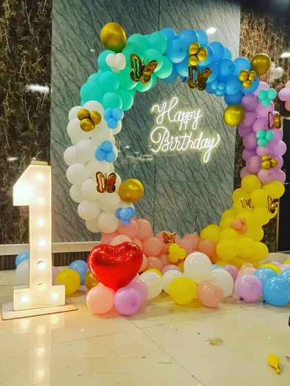 A colorful butterfly-themed first birthday. The pastel balloon ring is decorated with butterfly stickers and includes a large light-up number '1'.