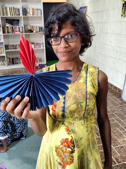 A girl proudly shows off the paper 'diya' (lamp) she made. These crafts not only celebrate the festival but also give children a sense of accomplishment.