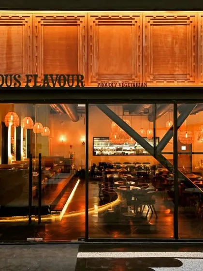 The facade is the first chapter of a brand's story. For the Indus Flavour restaurant, we designed a striking entrance that blends modern architectural lines with traditional motifs, featuring custom wood paneling and warm, inviting exterior lighting that draws patrons in.