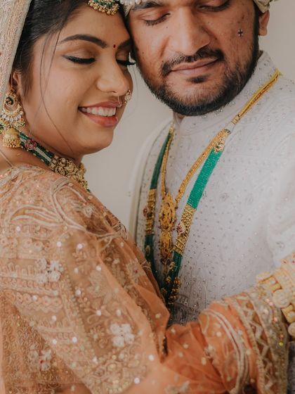 A close-up of the couple's embrace, focusing on their joyful expressions and the intricate details of their wedding attire and jewelry.