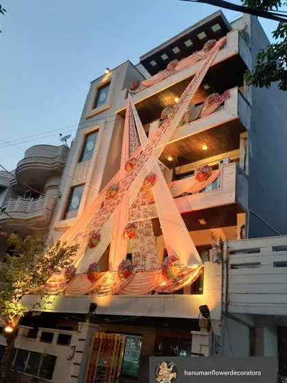 An elegant evening look for a home's exterior decoration. I used flowing peach-colored drapes accented with floral baskets and warm lighting to give the building a grand and celebratory appearance at night.