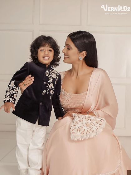 A precious moment between mother and son, with him looking absolutely dapper in our black velvet embroidered Indo-western jacket.