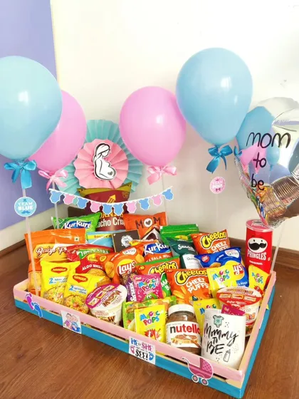 Sometimes a mom-to-be just needs her favorite snacks. This hamper is loaded with chips, chocolates, Nutella, and more, all presented with a fun 'Mom to be' theme.