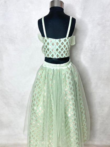 A closer look at the girl's soft mint lehenga, showing the delicate net overlay on the skirt and the simple, elegant crop top.