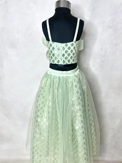 A closer look at the girl's soft mint lehenga, showing the delicate net overlay on the skirt and the simple, elegant crop top.