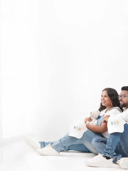 A relaxed moment from a casual maternity session. The couple is looking towards the future, with cute "Mom" and "Dad" hats adding a fun detail.
