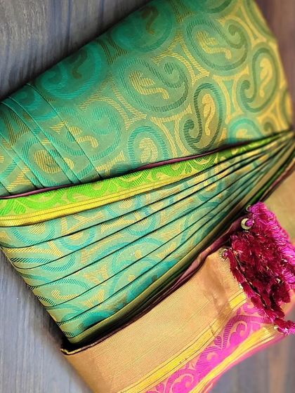 A stunning green and pink Kanjivaram silk saree, pre-pleated and box-folded. I ensure the thick zari border is pleated neatly for a sharp look.